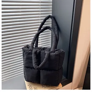 Detail of black quilted padded tote bag with modern puffy texture and shoulder straps