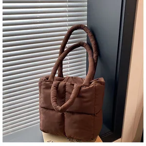Detail of dark brown quilted puffer tote bag with soft padded handles and nylon texture