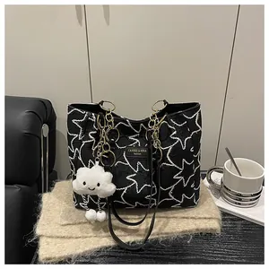 Detail of star-patterned tote bag with gold chain and white cloud plush charm accessory