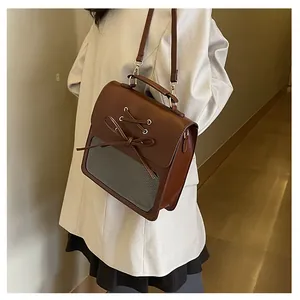 Brown leather JK style messenger bag featuring a clear window and bow detail shown on a model