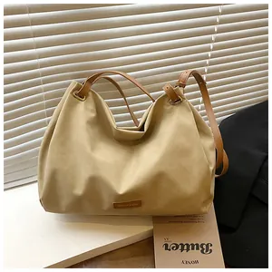 Detail of khaki tote bag with brown leather straps next to fashion magazine