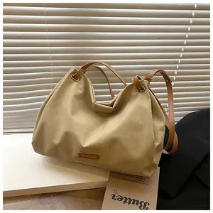 Detail of khaki tote bag with brown leather straps and gold metal hardware accents