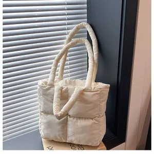 Close-up of beige quilted puffer tote bag with large square stitching on a windowsill