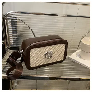 Detail of trendy crossbody bag featuring contrast stitching and silver M logo on a metal rack