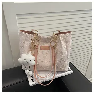 Detail of pink jacquard tote bag with star texture and plush cloud keychain