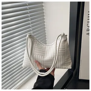 Détail d'un sac porté épaule blanc avec texture gaufrée et poignées rondes en velours