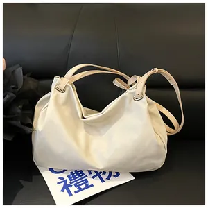 Detail of creamy white faux leather tote bag with soft pleats and gold metal rings