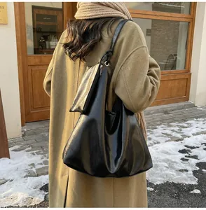 Detail of a large black hobo tote bag with a small matching pouch on a winter shoulder