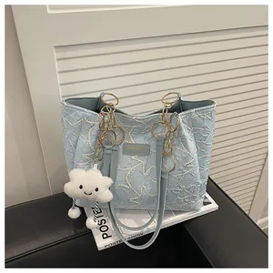Detail of light blue quilted tote bag with wavy stitching and cloud charm accessory