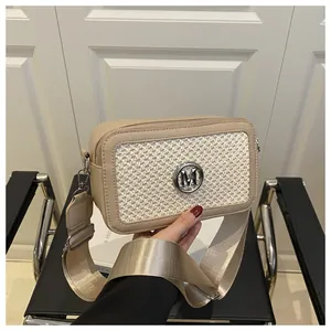 Detail of woven texture beige crossbody bag with silver M logo and wide strap