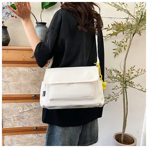 Détail du sac bandoulière en nylon blanc avec rabat et breloque jaune dessin