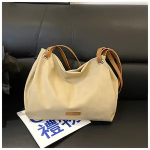 Detailed macro view of the cream tote bag with brown leather handles on a leather sofa