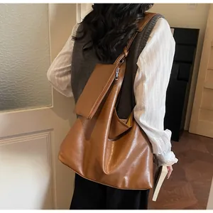 Brown faux leather tote bag with matching coin purse shown on shoulder for daily commute