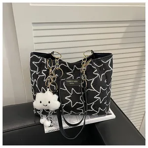 Detail of black pleated tote bag with white star embroidery and gold chain hardware