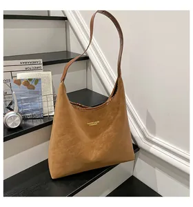 Detailed view of dark brown leather tote bag with gold logo and wide shoulder strap