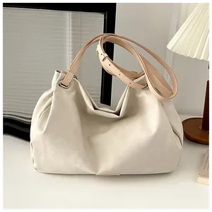 Detail of off-white tote bag showing textured soft faux leather and adjustable brown strap