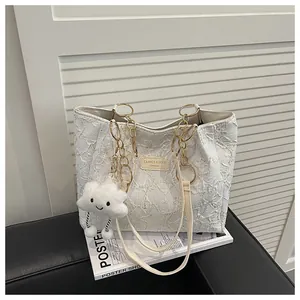 Detail of white textured tote bag with gold chain strap and plush cloud charm