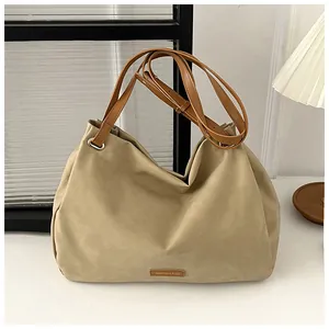 Detail of light khaki tote bag with adjustable brown straps and brand logo plate