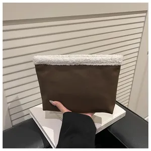 Dettaglio di una borsa tote marrone con bordo in sherpa bianco tenuta in mano per la misura