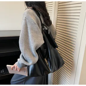 Detail of black leather tote bag with metal eyelets and zipper shoulder strap detail