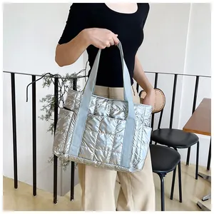 Detail der gesteppten Umhängetasche in Metallic-Silber mit weicher Textur und grauen Trägern