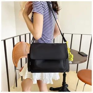 Détail du sac bandoulière en nylon étanche avec poche latérale et étiquette mode