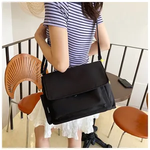 Vue latérale d'un grand sac bandoulière noir en nylon avec étiquette sur un mannequin