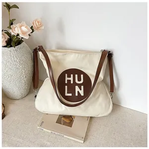 Detail of cream canvas tote bag with brown leather patch and shoulder strap for daily use