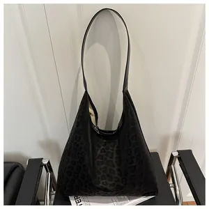 Detailed view of black leopard print faux leather shoulder bag on a stylish chair