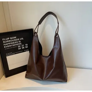 Detail of deep brown PU leather tote bag with silver metal eyelets and soft texture