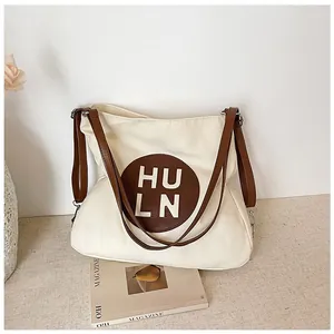 Detailed view of off-white canvas tote bag with brown leather straps and circular logo