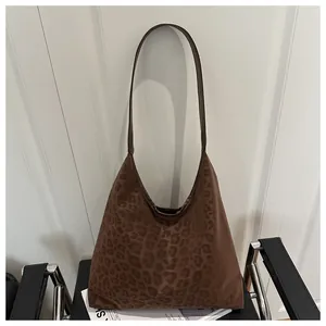 Detail of a large leopard print tote bag with soft suede texture on a leather chair