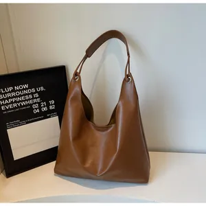 Detail view of large brown faux leather hobo tote with metallic rings and wide strap