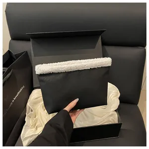 Dettaglio di una borsa tote nera con bordo in peluche bianco in confezione regalo