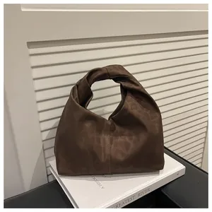 Detail view of brown silk tote bag with twisted knot handle on minimalist background