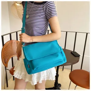 Détail de la grande besace en nylon bleu vif avec étiquette tissée de mode