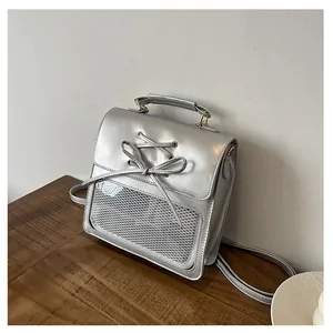 Detail of silver metallic backpack featuring ribbon bow and transparent display pocket