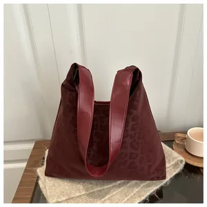 Macro view of burgundy leopard print texture and wide leather strap on tote bag