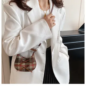 Mini plaid wool saddle bag with bow details and brown leather strap on female model