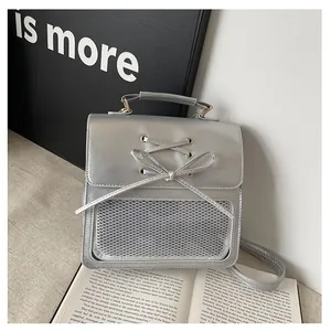 Detail of silver metallic bag featuring a bow ribbon and transparent mesh front pocket