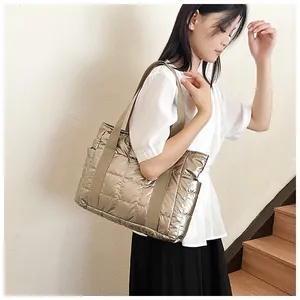 Detail der metallischen Stepp-Tasche mit Glanzeffekt und breitem Textilgurt