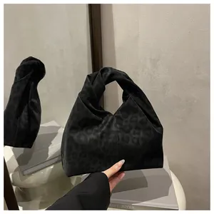 Detailed view of the knotted handle and subtle leopard print on black hobo bag