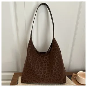 Detail of hobo shoulder bag featuring leopard print texture and brown leather strap