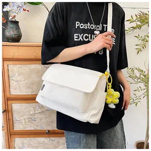 Détail d'un sac bandoulière en nylon blanc avec charme tournesol porté par un mannequin