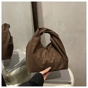 Detail of dark brown suede hobo bag with knotted handle and leopard print texture