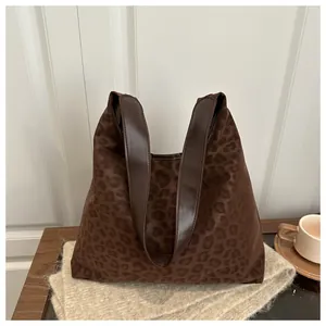 Detail of a large leopard print faux suede hobo bag with a dark brown leather shoulder strap