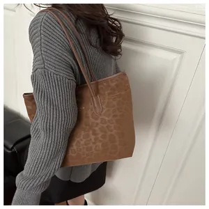 Detail view of large leopard print tote bag with gold logo and leather straps on model