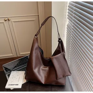Detail of a large coffee brown hobo bag with a matching pouch and metal eyelet design