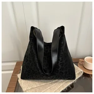 Detail of black leopard print tote bag on beige knit textile with lifestyle elements