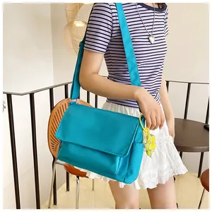 Détail de la sacoche en nylon turquoise avec breloque fleurie et bandoulière large